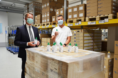 5.000 Fläschchen Desinfektionsmittel bekam der GLKN von einer britischen Firma gestiftet, die nun den Mitarbeitern zur Verfügung gestellt werden. Über die großzügige Spende freuen sich GLKN-Geschäftsführer Bernd Sieber und Chefapotheker Peter Buchal. Bild: Jagode