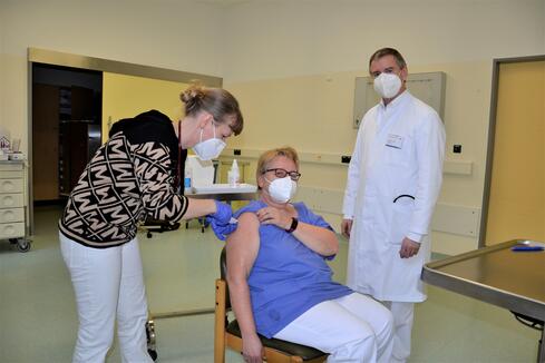 Dr. Sabine Hempel impft Dr. Sabine Schollmeyer gegen das Corona-Virus. Die Zweitimpfung erfolgt in ungefähr zwölf Wochen. Chefarzt Prof. Frank Hinder, Ärztlicher Direktor und Impfkoordinator am Klinikum Singen, freut sich, dass es mit dem Impfungen des Klinikpersonals vor Ort endlich losgegangen ist. Bild: Jagode